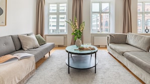 A modern living room with two sofas, a coffee table, and a vase of flowers. - Regent 3 - Popular 3-Bdr Apt with Balcony in Centre (København)