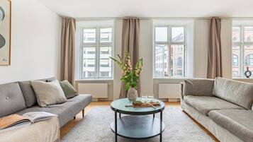 A modern living room with two sofas, a coffee table, and a vase of flowers.