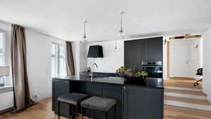 A modern kitchen with a central island, dark cabinetry, and pendant lighting. - Regent 7 - Large 3 Bdr Apt with Balcony in City Centre (København)