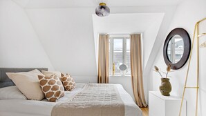 Un dormitorio con cama, cómoda, espejo y ventana con cortinas.