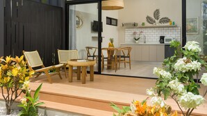 Un patio moderno al aire libre con muebles de madera, una mesita y plantas en macetas.