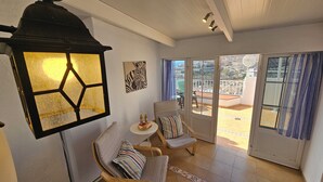 A room with a large window, a table with two bottles, a chair with a striped pillow, and a wall with a zebra print artwork. - Duplex • Walk to Anfi Beach • 3 Pools • Large Terrace (Los Caideros)