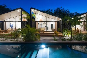 Una casa moderna con piscina, zona de estar exterior y patio.