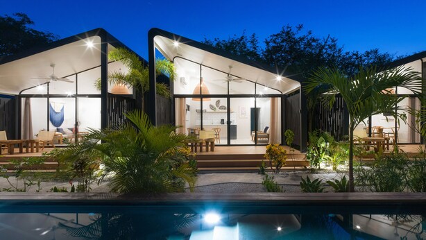 A modern house with a pool, outdoor seating, and a patio area.