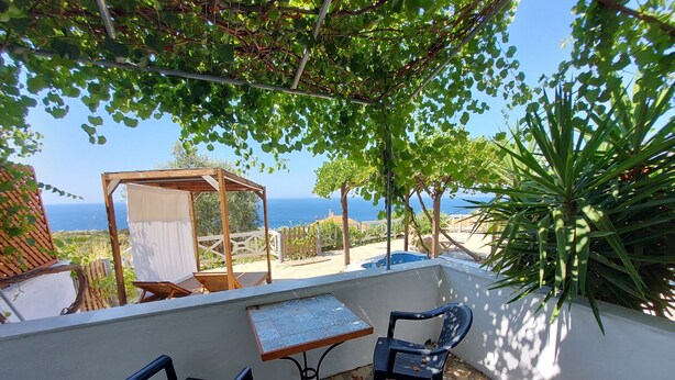 A patio with a table and chairs, a pergola, and a view of the sea. - Samos Island - Panorama Apartment with Jacuzzi (Koumeika)