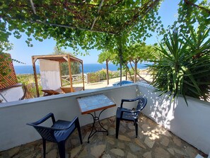 Une terrasse avec une table et des chaises, une pergola et une vue sur la mer.