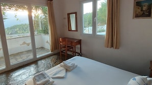 Une chambre à coucher avec un lit, un bureau, une chaise et une fenêtre avec des rideaux.