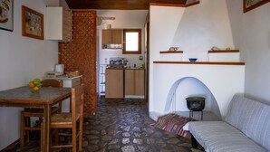 Una cocina compacta con armarios de madera, una mesa de comedor con sillas y un piso de piedra.