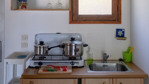 Una cocina compacta con armarios de madera, una estufa a gas, un lavamanos y una ventana sobre el lavamanos.