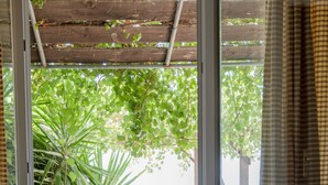 Una habitación con vista a un balcón, mobiliario de mimbre y un farol.
