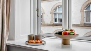 A window with a view of a building, a bowl of fruit, two mugs, and a plate with pastries on a windowsill. - Regent 4- Cute 1-Bdr Apt in Centre of Copenhagen (København)