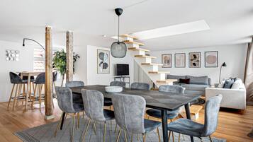 A modern living space with a dining area, a staircase, and a sofa.