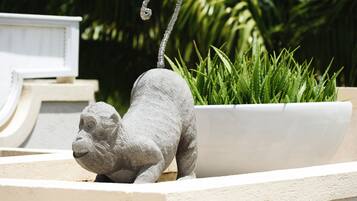 En skulptur av en apa, huggen i sten, placerad i en blomkruka.