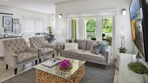Un salon moderne avec un canapé, des fauteuils, une table basse et un téléviseur.