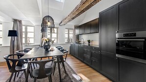 Eine moderne Küche mit dunklen Schränken, einem Holztisch und einer Kronleuchter.