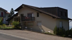 En toetages bygning med balkon, garage og en lille have.