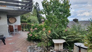 En patio med et stensæt bord, en træbænk og en pergola.