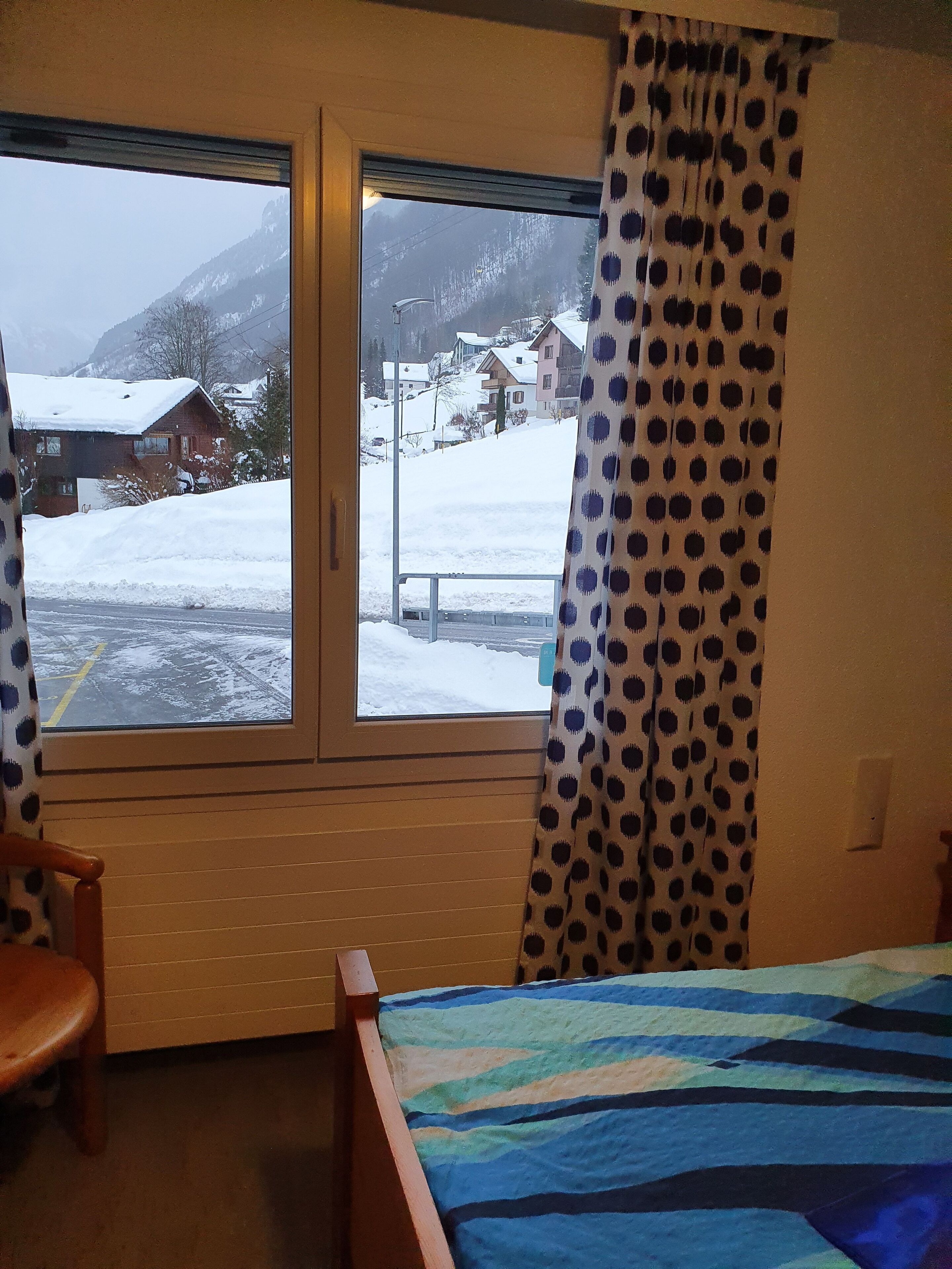 A room with a bed, a chair, and a window with curtains.