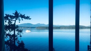 Vista de un lago tranquilo con un bote, rodeado de árboles y montañas.