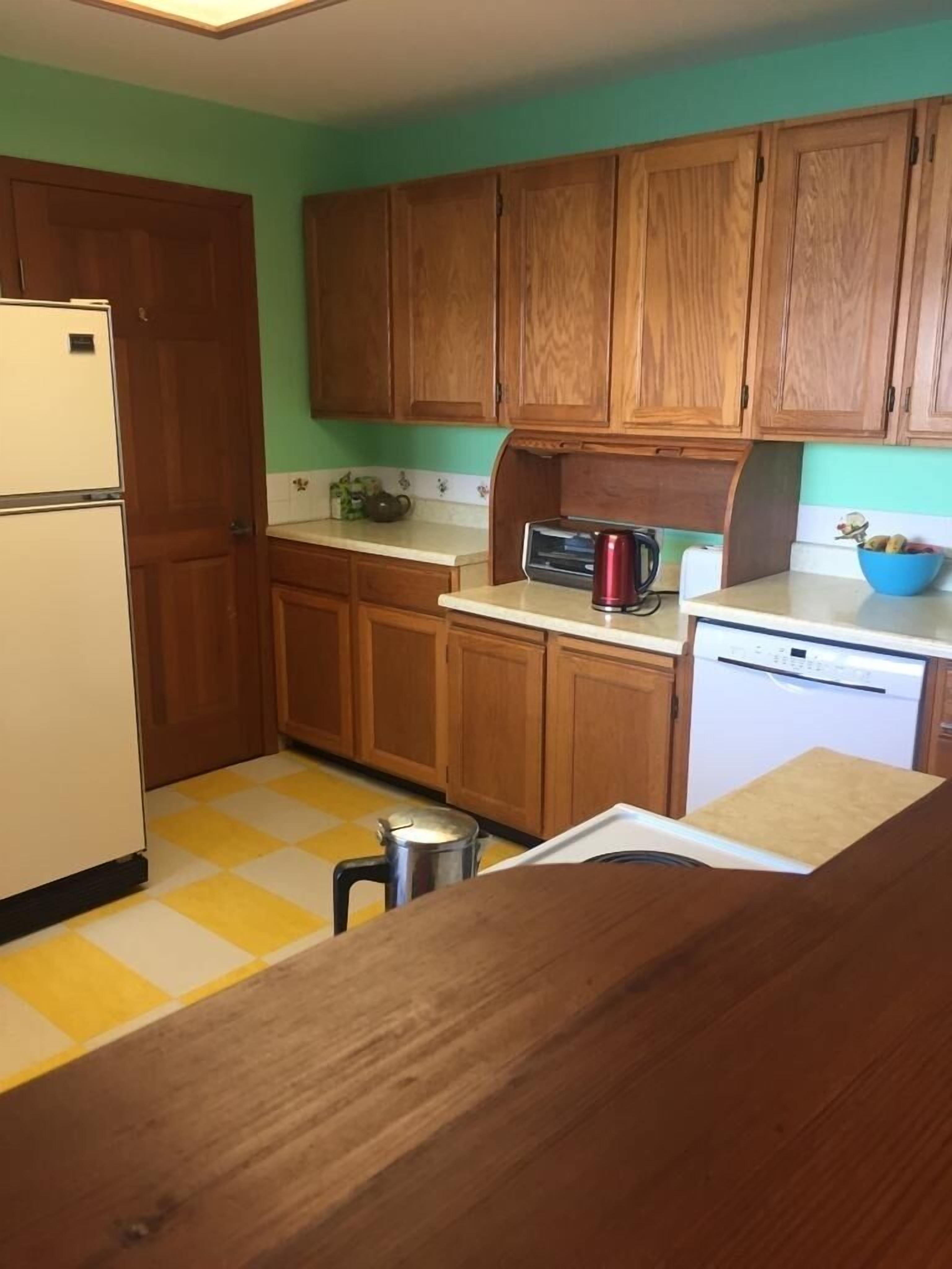 A kitchen with wooden cabinets, a refrigerator, a stove, and a sink.