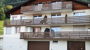 Un bâtiment à deux étages doté d’un balcon en bois, d’un garage et d’un espace de stationnement.