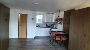 A modern kitchen with white cabinets, a dining table with chairs, and a wooden floor.