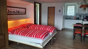 A compact room with a bed, a kitchenette, and a dining area.