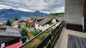 A balcony with a view of a mountain landscape and a lake.