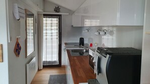 A modern kitchen with white cabinets, a built-in oven, and a coffee machine.