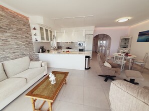 A modern living room with a sofa, a coffee table, and a dining area with chairs. - Spacious Apartment with Sea view! (Mogán)