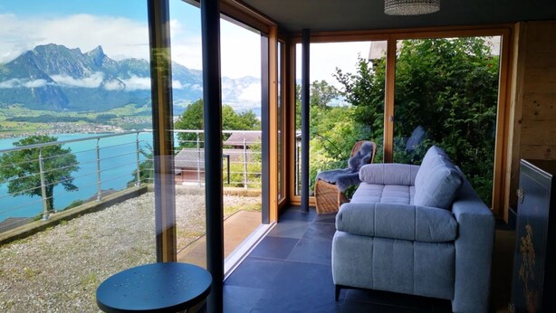 Un intérieur moderne doté d’une grande fenêtre offrant une vue panoramique sur les montagnes et un lac.