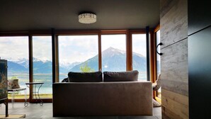 Un salon moderne doté d’une grande fenêtre donnant sur un paysage montagneux.