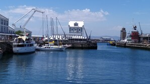 Ein Hafen mit vertäuten Booten, einem Kran und Gebäuden mit markanter Architektur.