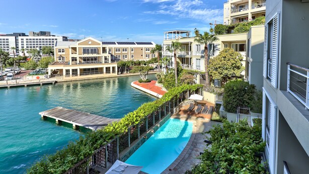 Ein Wohngebäude mit Pool, Steg und Blick auf das Wasser.