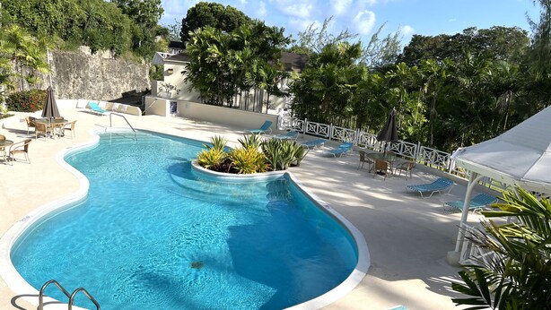 Une piscine agrémentée d’une petite cascade, entourée de chaises longues et d’un espace de détente abrité.