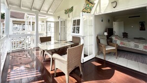 Une pièce spacieuse avec une grande table à manger, des chaises en osier et un coin repos confortable avec un lit.