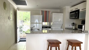 Une cuisine moderne dotée d’un îlot central, d’appareils électroménagers intégrés et offrant une vue sur l’extérieur.
