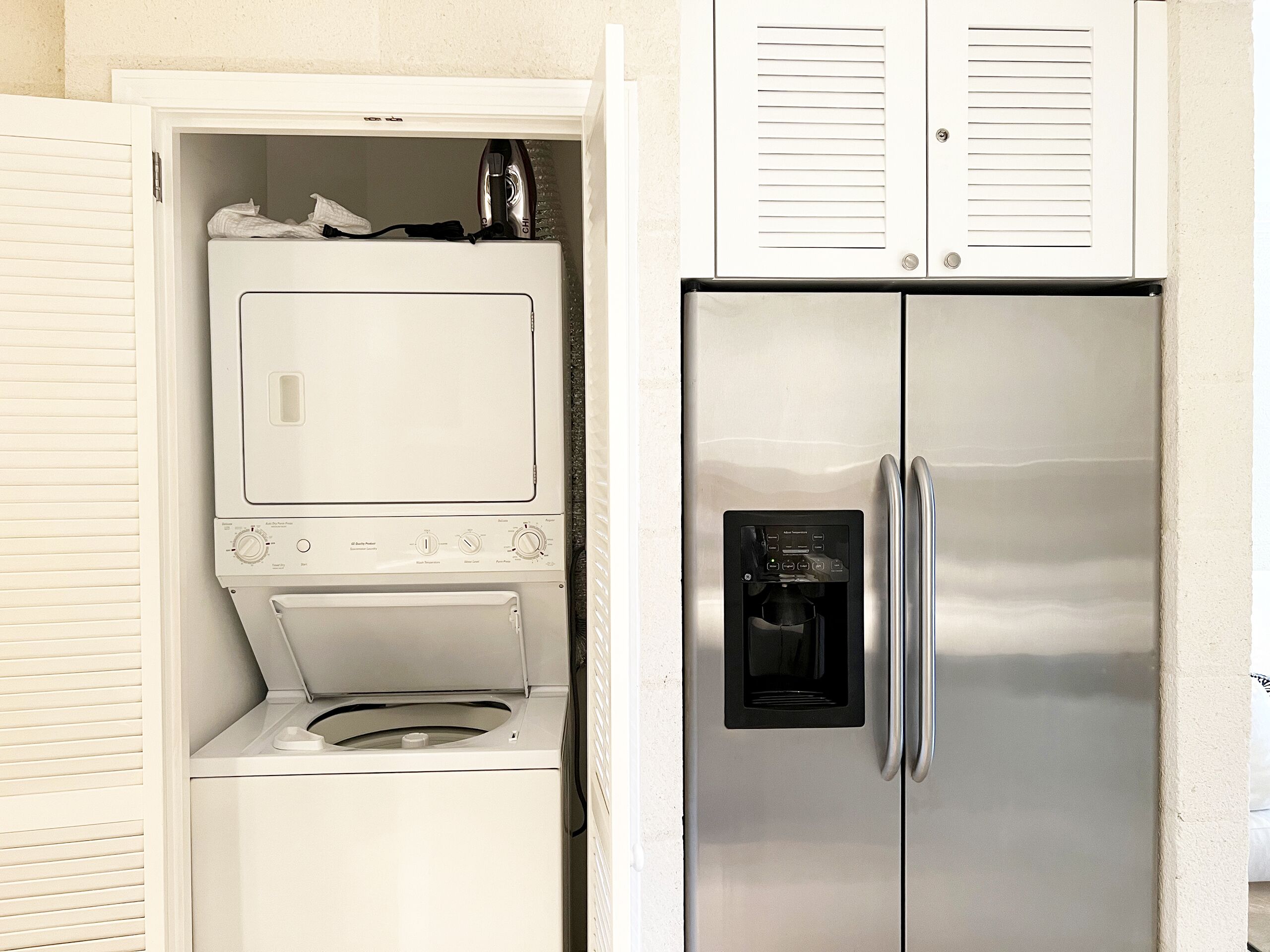 Uma cozinha compacta com máquina de lavar e secar embutidas, geladeira de aço inoxidável e micro-ondas.