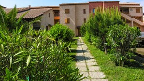 Un chemin menant à un bâtiment doté de nombreux balcons et d’un toit recouvert de tuiles.