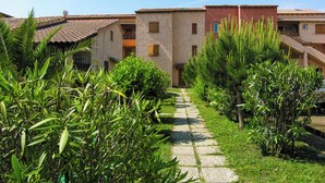 A pathway leading to a building with a tiled roof and multiple windows.