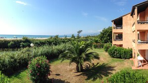A building with multiple balconies overlooking a garden and beach.