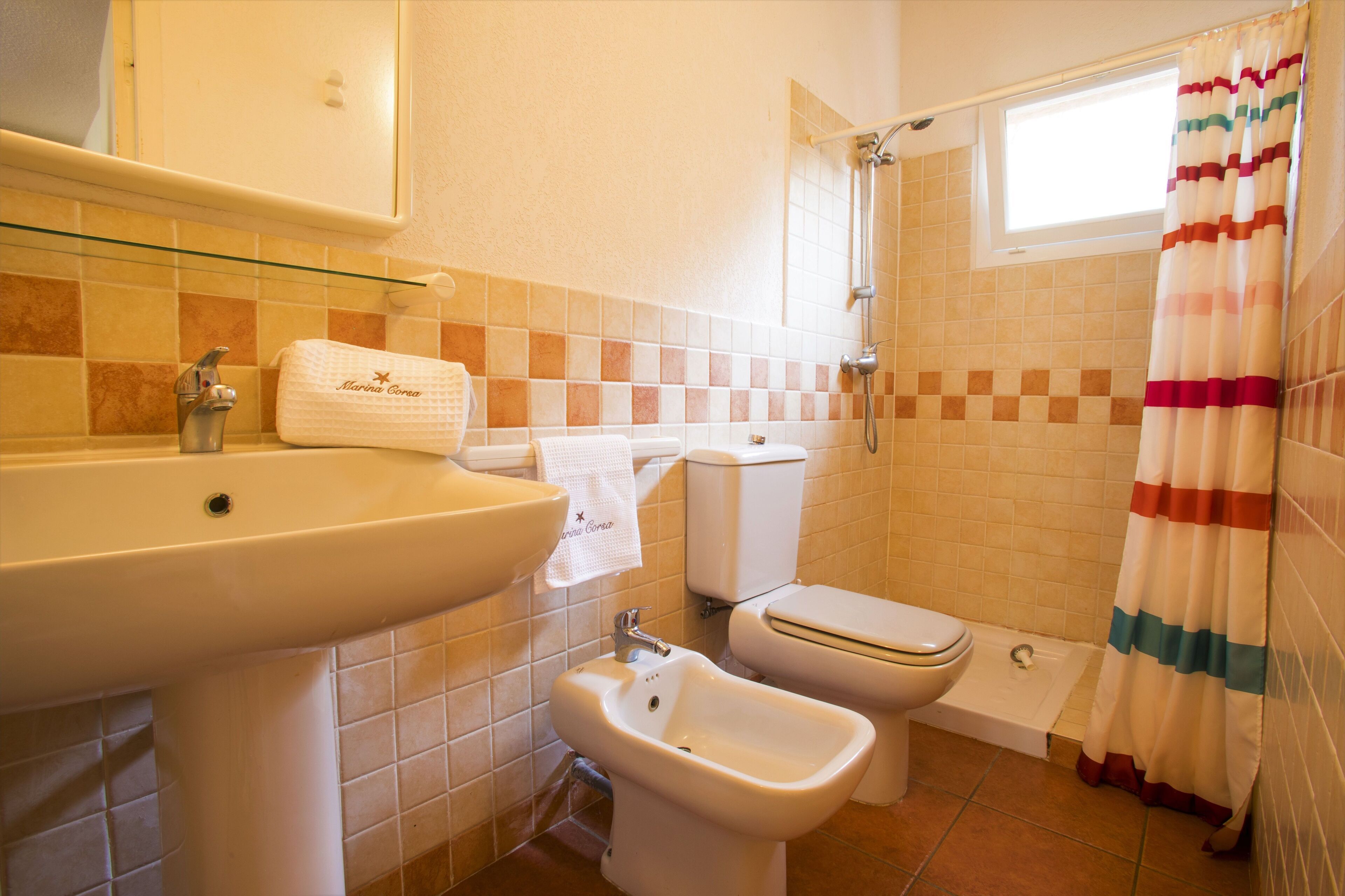 A bathroom with a sink, bidet, toilet, and shower.