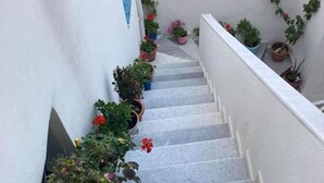 Een smalle trap met plantenpotten aan de linkerkant.