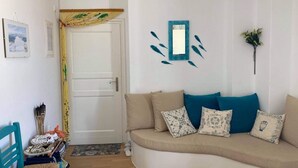 Een woonkamer met een bank, een deur en een spiegel aan de muur.