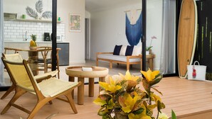 Un espace de vie moderne doté d’une porte vitrée donnant sur une cuisine, d’un coin repas avec une table ronde et d’un coin salon avec un canapé.
