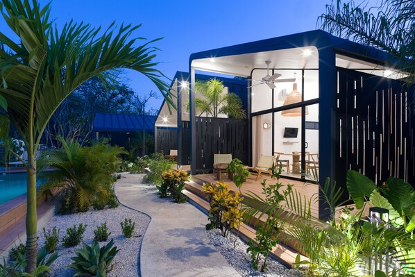 Une maison moderne dotée d’une piscine, d’un espace salon extérieur et de plantes tropicales.