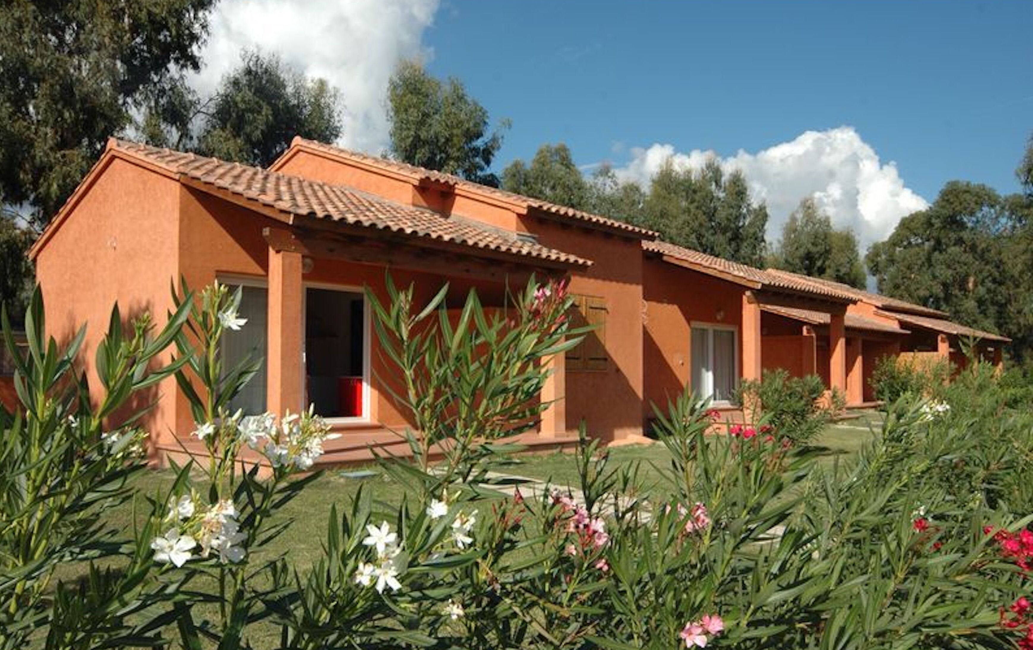 A row of terracotta-roofed buildings with a garden in the foreground.