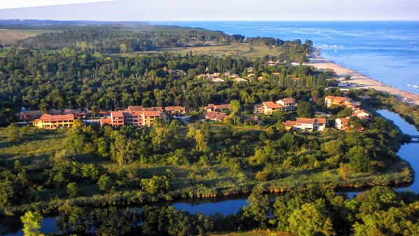 An aerial view of a resort with multiple buildings, a beach, and a river.