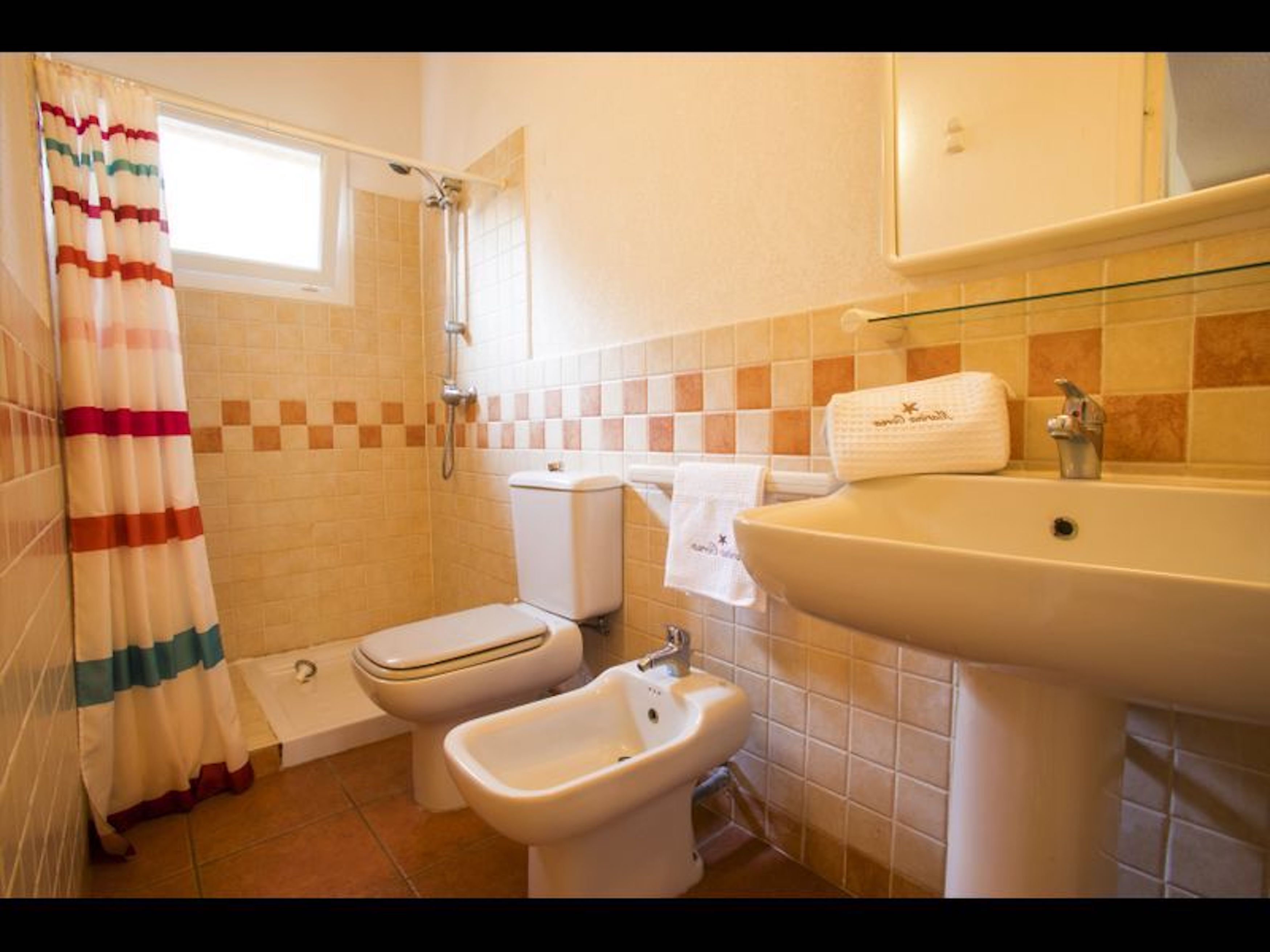A bathroom with a shower, toilet, bidet, and sink.