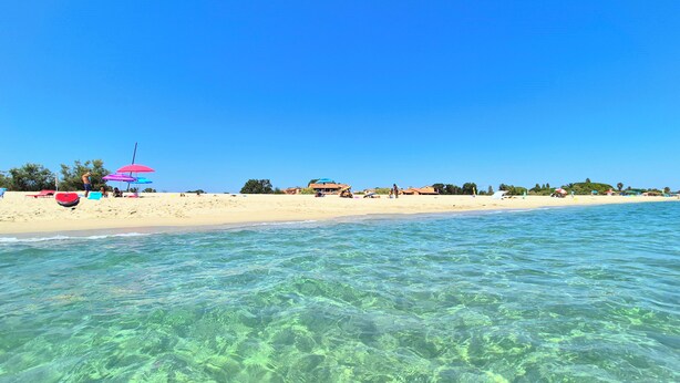 A beach with clear water, umbrellas, and beach huts. - Marina Corsa Residence 3rooms apartment 150 m from the beach - Ghisonaccia (Ghisonaccia)